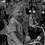 child, toddler, motorcycle, carousel, animal_figure, playground, outdoor, smiling, happy, riding, toy, seat, handlebar, clothing, shorts, hair, fun, daylight, amusement_park, black_and_white