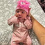 Jazmín joined the competition — help win amazing prizes! baby, infant, pink_clothing, headband, flower, bed, hand, adult_hand, floral_pattern, onesie, cute, newborn, lying_down, person, face, expression, indoor, soft_lighting, sleepwear, young_child