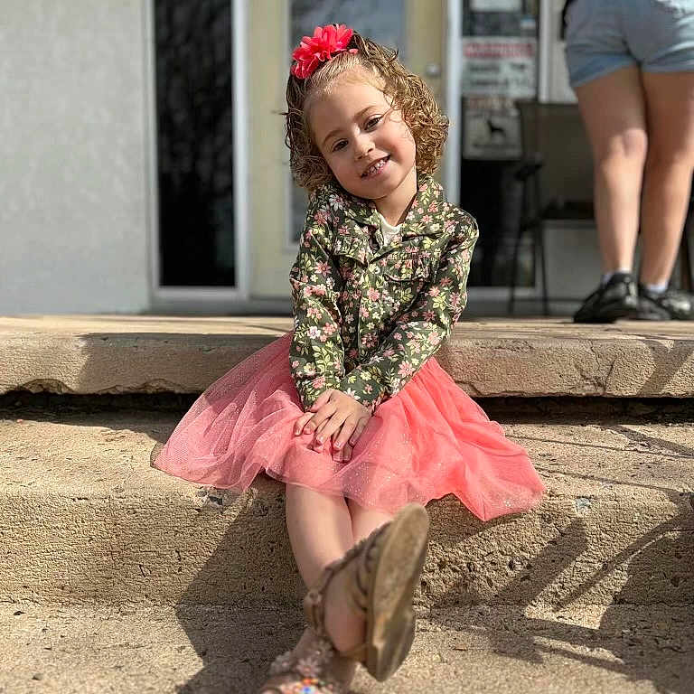 Makenzie is registered to the contest to win money with this photo: child, clothing, curlyhair, dress, face, female, footwear, girl, hair, head, pants, person, photography, portrait, sandal, shoe, shorts, sitting, skirt, sleeve