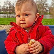 Jules participe au concours pour gagner de l'argent avec cette photo : baby, blue_eyes, bread, child, coat, cute, expression, face, grass, hair, hands, nature, outdoor, park, pond, portrait, red_jacket, snack, toddler, winter_coat