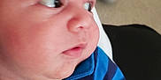 Quentin Maximus is registered to the contest to win money with this photo: baby, infant, face, curious, blue_shirt, striped_shirt, lion_patch, blanket, arm, skin, child, young, portrait, indoor, casual_clothing, cute, newborn, person, looking_away, closeup