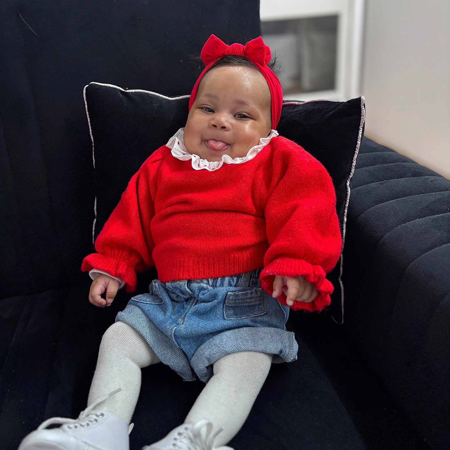 Kyanna a rejoint le concours — aidez-le/la à gagner de superbes lots ! baby, black_cushion, child, childhood, couch, cozy, cute, denim_shorts, fashion, happy, headband, indoor, infant, portrait, red_sweater, seated, smiling, tongue_out, white_shoes, white_tights