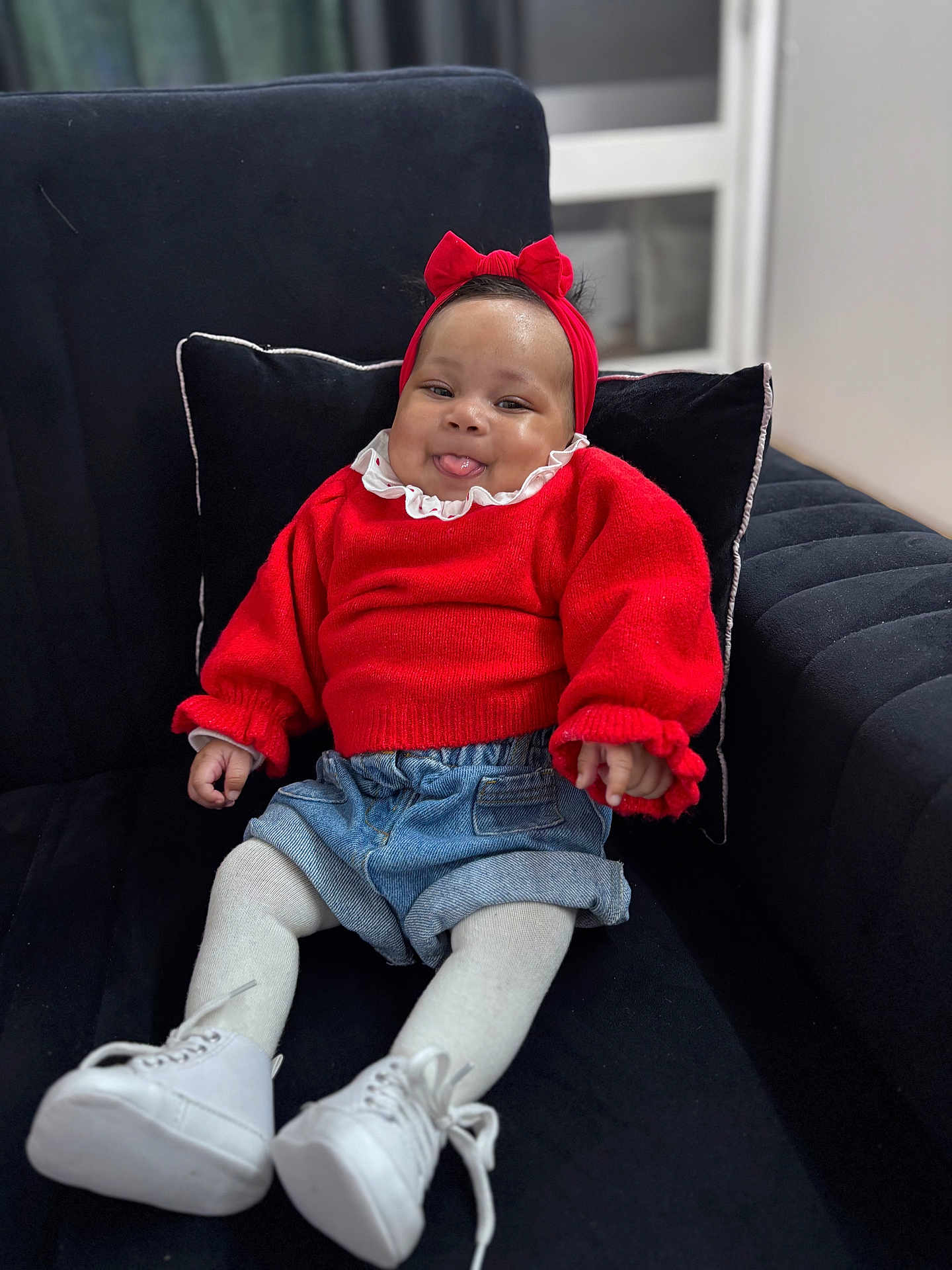 Kyanna a rejoint le concours — aidez-le/la à gagner de superbes lots ! baby, black_cushion, child, childhood, couch, cozy, cute, denim_shorts, fashion, happy, headband, indoor, infant, portrait, red_sweater, seated, smiling, tongue_out, white_shoes, white_tights