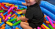 Luka joined the competition — help win amazing prizes! baby, black_clothing, blue_inflatable_pool, bright_colors, child, colorful_toys, curly_hair, cute, fun, happy, indoor, person, plastic_toys, play_area, playtime, portrait, sitting, smiling, soft_toys, toddler
