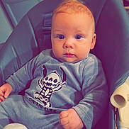 Raphaël participe au concours pour gagner de l'argent avec cette photo : baby, child, onesie, high_chair, blue_eyes, indoor, wooden_wall, cozy, infant, cute, portrait, skeleton_graphic, clothing, seat, furniture, young_child, face, hand, foot, expression