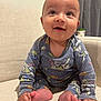 baby, child, smiling, blue_onesie, cartoon_characters, sitting, couch, beige, happy, indoors, feet, hands, head, face, curtain, potted_plant, cozy, cute, portrait, infant