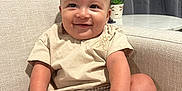 Osiah joined the competition — help win amazing prizes! baby, child, smiling, couch, indoor, clothing, socks, shorts, shirt, face, hand, legs, furniture, curtain, plant, table, living_room, happy, sitting, person