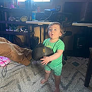 Sunshyne is registered to the contest to win money with this photo: toddler, child, barefoot, green_clothing, boot, carpet, indoor, furniture, desk, chair, shelf, shoes, window, television, expression, person, room, floor, toy, lighting