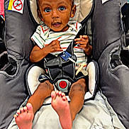 Kelvin joined the competition — help win amazing prizes! baby, child, stroller, car_seat, infant, foot, feet, clothing, seatbelt, safety_harness, curly_hair, wide_eyes, indoor, person, cute, expression, hands, head, skin, footwear