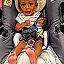 baby, child, stroller, car_seat, infant, foot, feet, clothing, seatbelt, safety_harness, curly_hair, wide_eyes, indoor, person, cute, expression, hands, head, skin, footwear