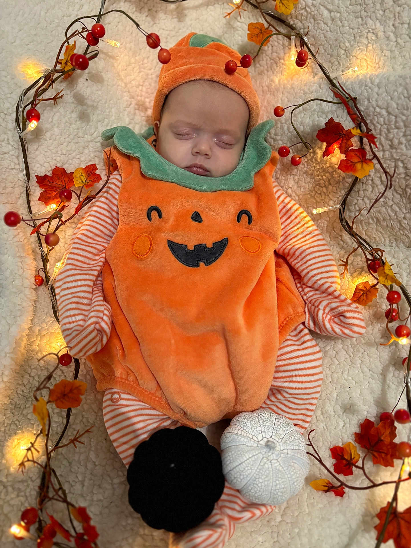 Arabella is registered to the contest to win money with this photo: baby, sleeping, pumpkin_costume, autumn, fairy_lights, decorative_leaves, blanket, orange, white, black, holiday, festive, cozy, infant, cute, seasonal, soft, child, portrait, holiday_decoration