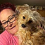 Sally is registered to the contest to win money with this photo: animal, cabinet, close_up, cozy, curious, curly_hair, cute, dog, face, friendly, fur, glasses, home, indoor, person, pet, pink_shirt, portrait, smile, woman
