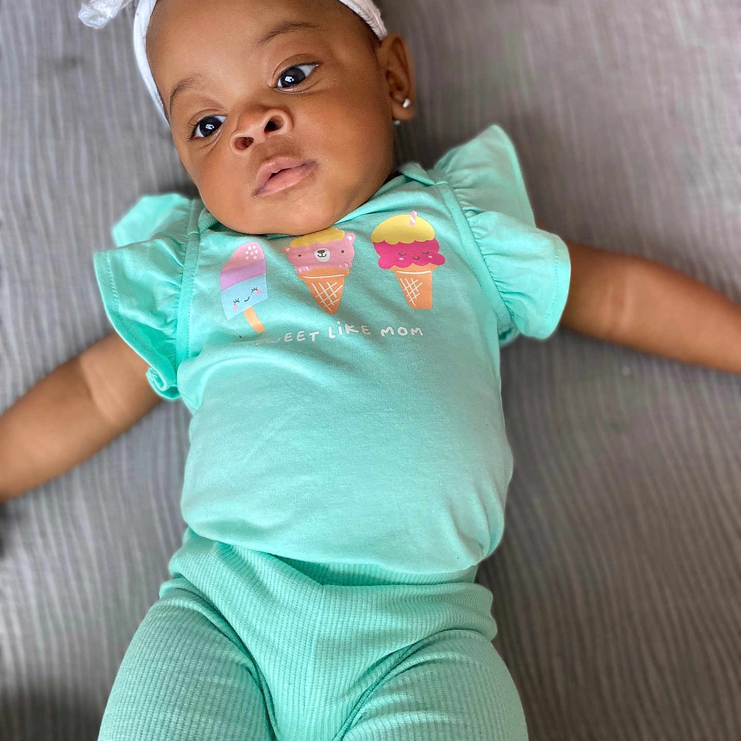 Jamorah is registered to the contest to win money with this photo: baby, bow, child, clothing, curious, cute, ears, fabric, face, headband, ice_cream_graphic, indoor, infant, lying_down, mint_green, pants, person, portrait, shirt, soft_texture