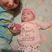 Harper is registered to the contest to win money with this photo: baby, child, newborn, sibling, smiling, cute, pacifier, pink_hat, floral_pants, blanket, lying_down, family, indoor, toddler, clothing, face, love, happy, portrait, infant
