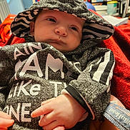 Ezekiel Edward joined the competition — help win amazing prizes! baby, hood, sweater, striped, hand, foot, blanket, red, indoor, clothing, infant, person, portrait, cute, face, small, relaxed, cozy, warm, expression