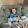 John is registered to the contest to win money with this photo: child, boy, smiling, blanket, couch, indoor, cozy, happy, toddler, blue_shirt, plush, home, floor, wall, comfort, seated, portrait, casual, furniture, cute