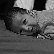 Eyden a rejoint le concours — aidez-le/la à gagner de superbes lots ! baby, infant, face, smiling, tongue_out, lying_down, black_and_white, close_up, portrait, soft_texture, clothing, cute, happy, child, head, skin, young, person, indoors, expression