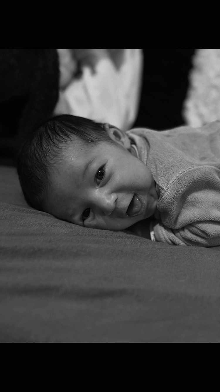 Eyden a rejoint le concours — aidez-le/la à gagner de superbes lots ! baby, infant, face, smiling, tongue_out, lying_down, black_and_white, close_up, portrait, soft_texture, clothing, cute, happy, child, head, skin, young, person, indoors, expression