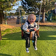 Ray joined the competition — help win amazing prizes! toddler, child, swing, playground, outdoor, smiling, blonde_hair, sneakers, baby_swing, grass, trees, sunlight, park, fence, clothing, happy, daytime, person, casual, fun