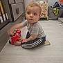 barefoot, cabinet, car, child, clothing, curious, floor, gray_shirt, home, indoor, laundry_basket, light_floor, motion_blur, pants, play, red, smartphone, toddler, toy, wooden_toys