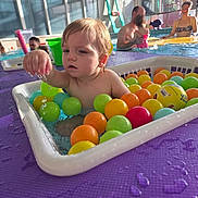 Raphaël a rejoint le concours — aidez-le/la à gagner de superbes lots ! adult, baby, bath_toy, child, colorful_balls, curiosity, family, indoor_pool, parent, plastic_balls, plastic_container, playtime, poolside, purple_mat, splash, sunlight, swimwear, toddler, water, window