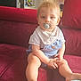 baby, bib, blonde_hair, casual_clothing, child, couch, cute, furniture, home, indoor, infant, kitchen, overalls, pacifier, person, relaxed, sitting, soft_lighting, toddler, young_child