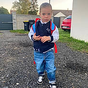 Ziane a rejoint le concours — aidez-le/la à gagner de superbes lots ! backpack, boy, car, casual_clothing, child, daylight, driveway, grass, gravel, jacket, jeans, outdoor, person, sky, sneakers, standing, suburban, trash_bins, tree, young