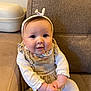Emy a rejoint le concours — aidez-le/la à gagner de superbes lots ! baby, bow, child, chubby_cheeks, clothing, couch, cute, eyes, furniture, hands, headband, indoor, infant, legs, onesie, portrait, sitting, smile, sofa, textile
