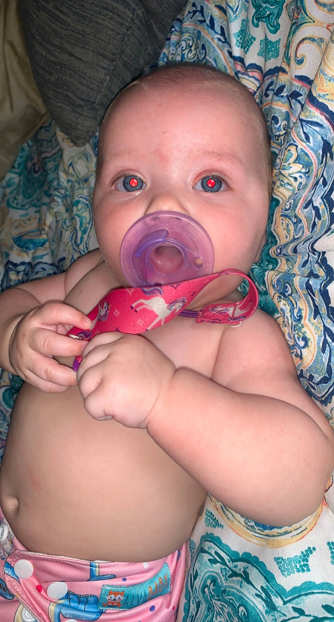 Audree is registered to the contest to win money with this photo: arm, baby, baby_toddler_clothing, blue, cheek, comfort, eye, finger, gesture, head, human_body, iris, lip, mouth, nose, person, pink, purple, skin, stomach