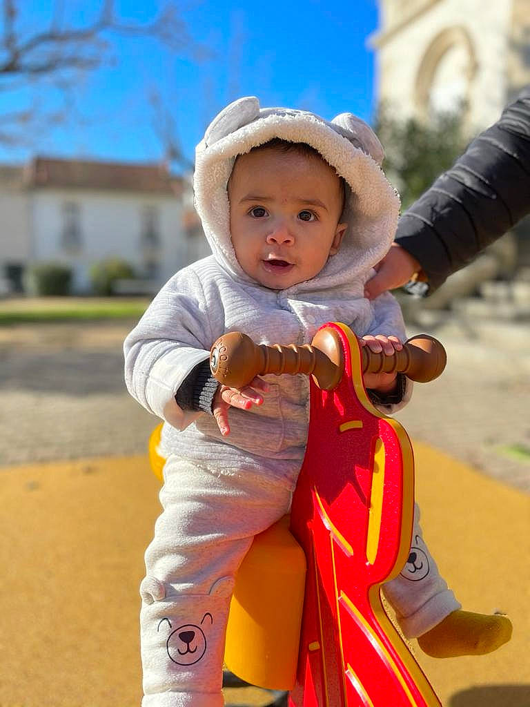 Elio a rejoint le concours — aidez-le/la à gagner de superbes lots ! baby, baby_toddler_clothing, child, fun, gesture, happy, hat, leisure, people_in_nature, person, plant, public_space, recreation, sitting, sky, sleeve, street_fashion, sun_hat, toddler, tree