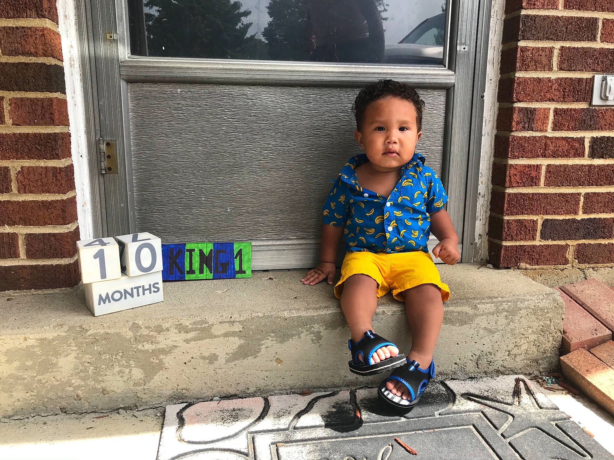 Javon is registered to the contest to win money with this photo: child, cool, door, footwear, home, house, people, person, photography, plant, play, shoe, sitting, smile, snapshot, t_shirt, toddler, vacation, vehicle, wall