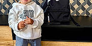 Swanny participe au concours pour gagner de l'argent avec cette photo : child, smiling, indoor, hoodie, jeans, sneakers, backpack, nike, braided_hair, floor_tiles, wooden_furniture, patterned_wall, standing, happy, casual_clothing, person, portrait, young_child, fashion, modern_interior