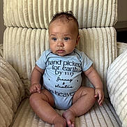 Houston is registered to the contest to win money with this photo: baby, infant, child, onesie, text, chair, plush, comfort, seated, cute, indoors, expression, skin, hands, feet, portrait, young, cozy, soft, casual
