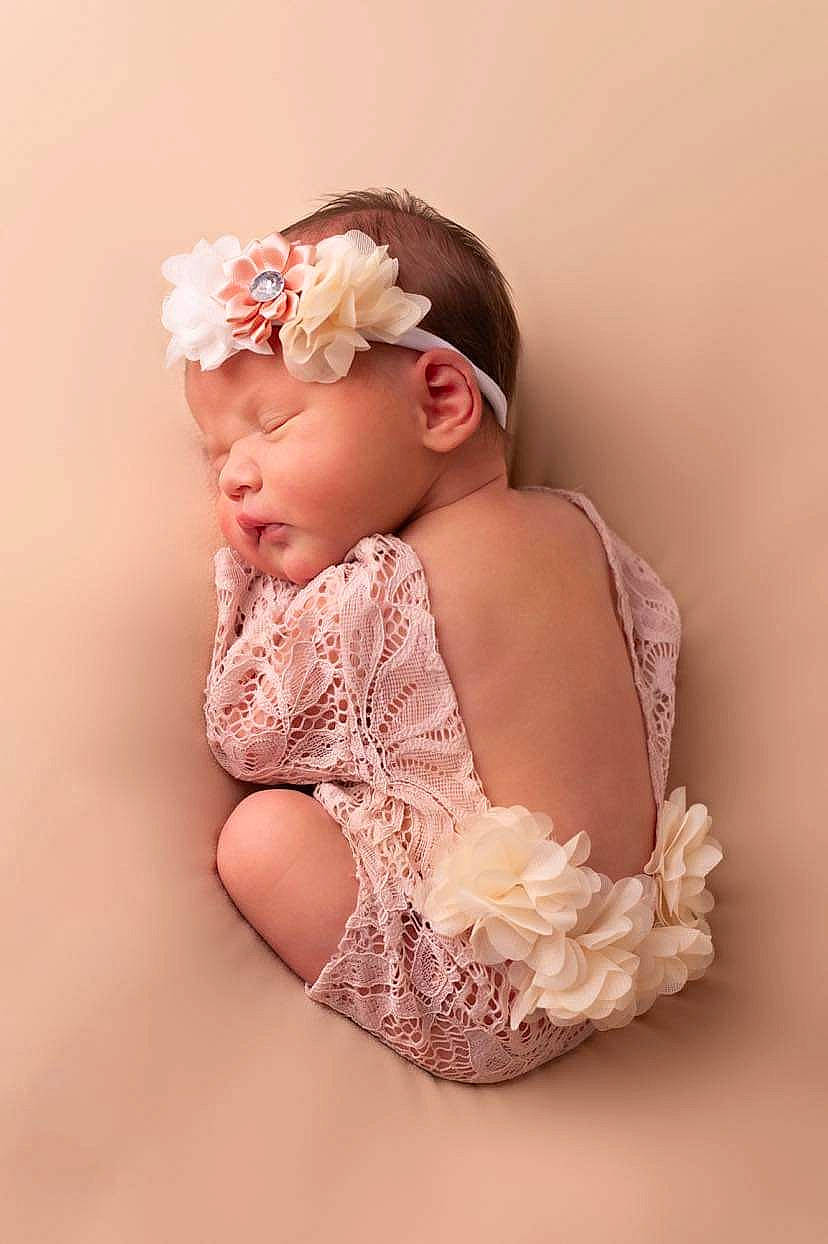 Avah participe au concours pour gagner de l'argent avec cette photo : baby, baby_toddler_clothing, bridal_accessory, child, dress, embellishment, fashion_accessory, flash_photography, hair_accessory, happy, headband, headpiece, headwear, human_leg, jewellery, peach, person, petal, portrait_photography, sitting