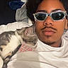 Timal participe au concours pour gagner de l'argent avec cette photo : person, cat, selfie, sunglasses, bed, bedroom, sleeping, relaxed, pet, portrait, indoor, blanket, pillow, white_shirt, facial_hair, curly_hair, eyewear, cozy, cuddling, photography