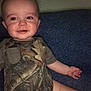 Logan is registered to the contest to win money with this photo: baby, bodypart, clothing, couch, cushion, face, furniture, happy, head, homedecor, laughing, military, pants, person, photography, portrait, shorts, sitting, smile, t_shirt