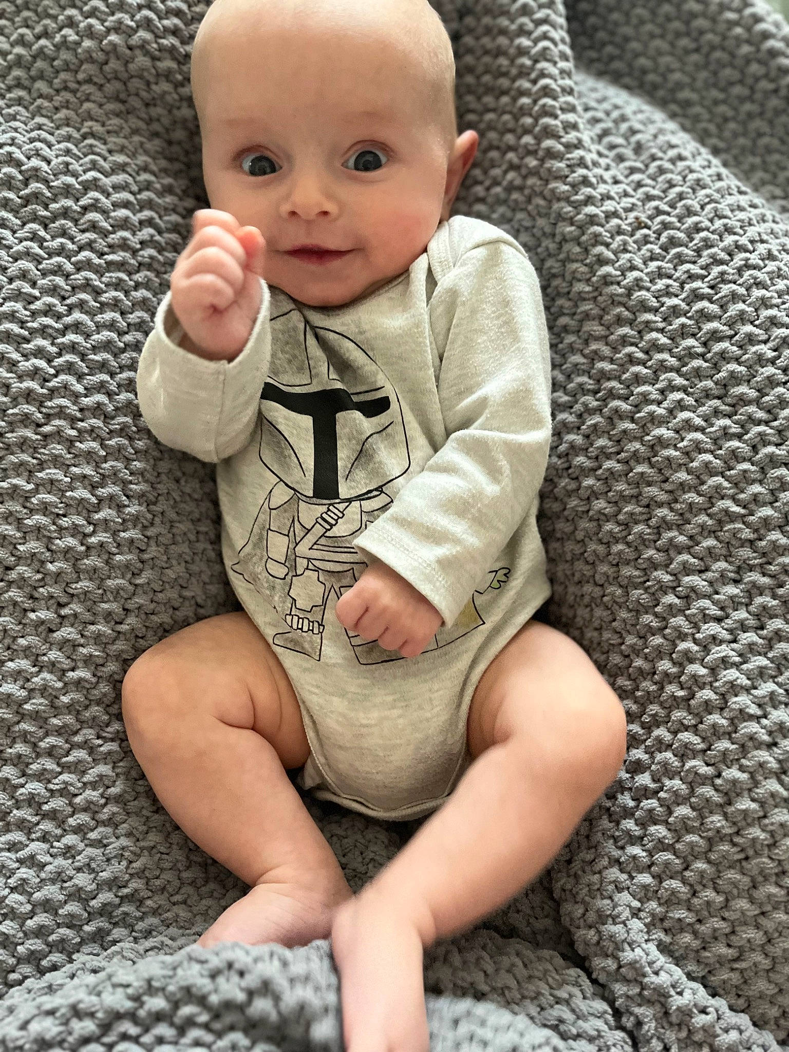 Andy is registered to the contest to win money with this photo: arm, baby, baby_toddler_clothing, cheek, chin, comfort, eye, flooring, foot, grey, hand, human_leg, knee, leg, nose, person, skin, sleeve, smile, textile