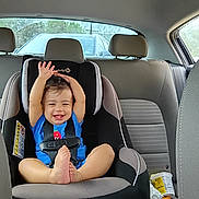 Emory is registered to the contest to win money with this photo: child, toddler, car_seat, car_interior, happy, smiling, baby, seatbelt, blue_shirt, foot, raised_hands, window, vehicle, headrest, seat, safety, indoor, person, casual, cute