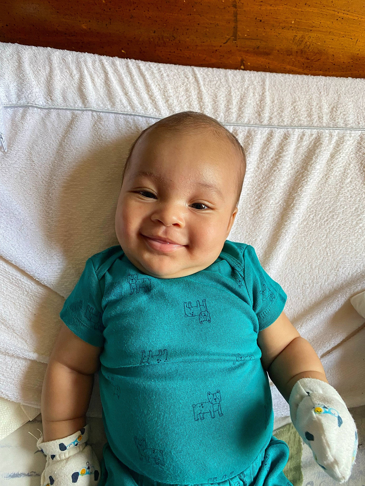Cairo is registered to the contest to win money with this photo: aqua, arm, baby, baby_toddler_clothing, cheek, child, clothing, comfort, face, facial_expression, happy, head, joy, linens, pattern, person, skin, sleeve, smile, t_shirt