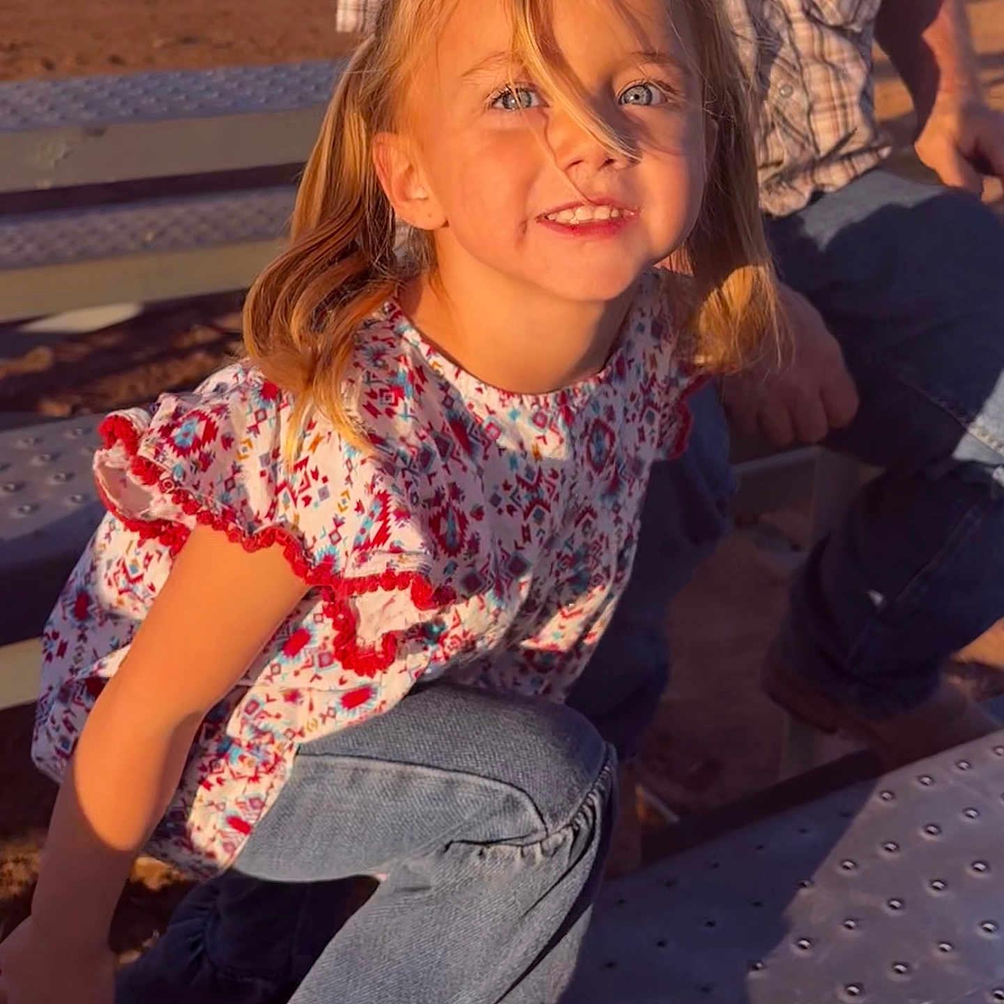 Arley joined the competition — help win amazing prizes! adult, bench, bleachers, blonde_hair, blue_eyes, casual_clothing, child, daylight, girl, happy, jeans, metal_surface, outdoor, patterned_shirt, pigtails, playful, portrait, shadow, smiling, sunlight