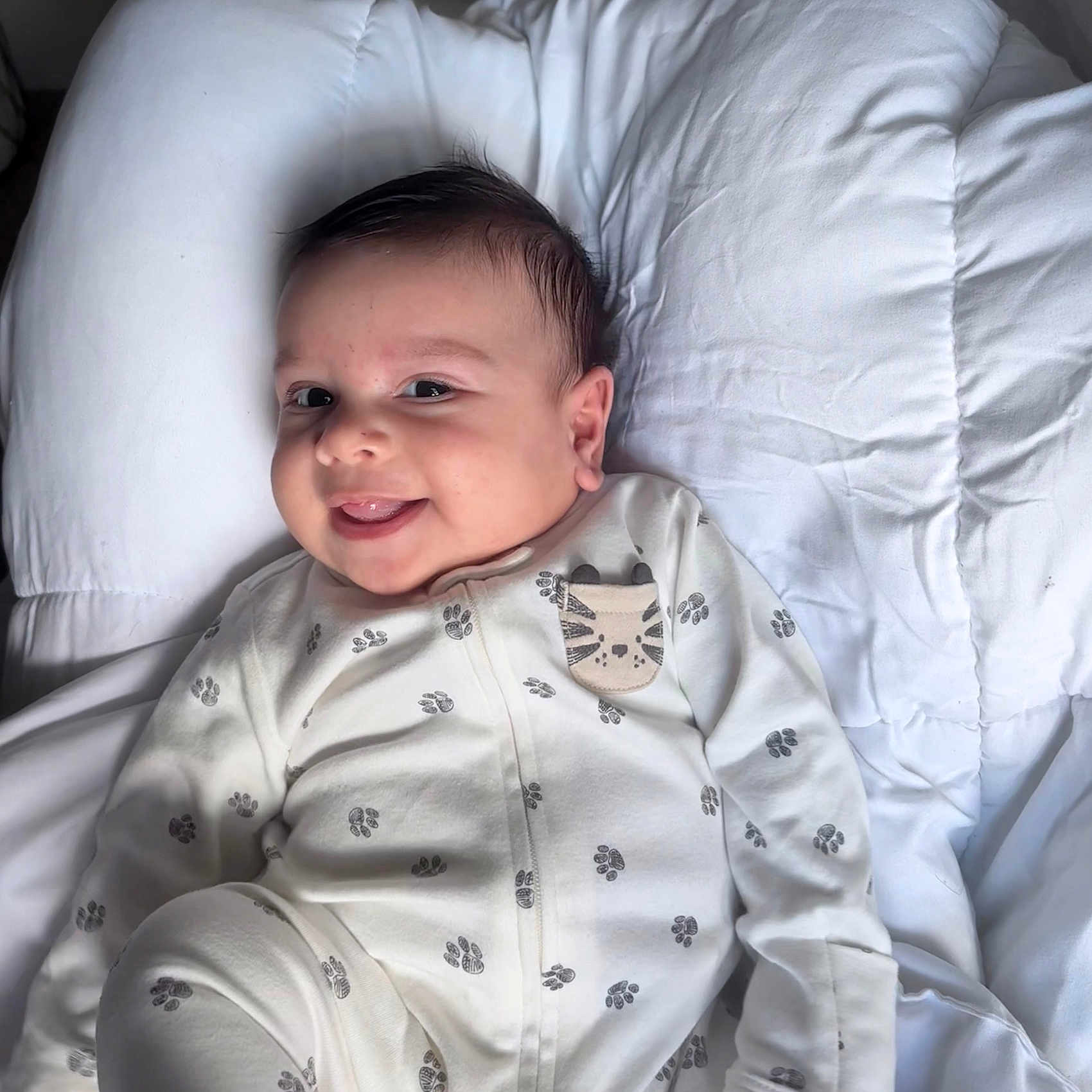 Eiden Machado joined the competition — help win amazing prizes! baby, child, close_up, cute, dark_hair, face, happy, head, indoors, infant, lying_down, onesie, paw_prints, portrait, sleepwear, small_hands, smiling, soft_lighting, tiger_patch, white_comforter