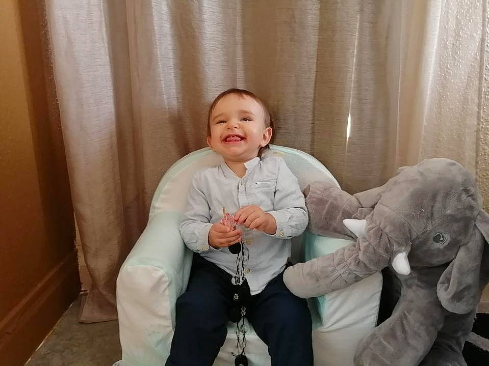 Timéo a rejoint le concours — aidez-le/la à gagner de superbes lots ! arm, baby, baby_toddler_clothing, barefoot, comfort, couch, curtain, foot, gesture, hand, happy, joy, knee, lap, leg, person, shoulder, smile, thigh, thumb