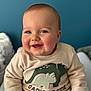 Mathis a rejoint le concours — aidez-le/la à gagner de superbes lots ! baby, blue_eyes, casual, cheeks, child, clothing, cozy, cute, dinosaur, face, happy, indoor, infant, person, portrait, sitting, smiling, sweatshirt, warm, young