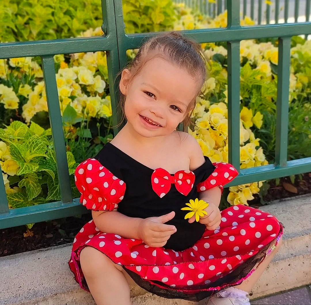 Talya participe au concours pour gagner de l'argent avec cette photo : baby_toddler_clothing, beauty, child, facial_expression, fence, flower, grass, happy, joy, morning, people_in_nature, person, petal, plant, product, sleeve, smile, t_shirt, thigh, toddler