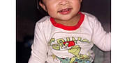 Jaylannie is registered to the contest to win money with this photo: baby, child, clothing, cozy, cute, cute_expression, face, festive, grinch, happy, holiday, indoors, long_sleeve, pajamas, portrait, red_trim, sitting, smiling, toddler, young_child