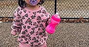 Jaylannie is registered to the contest to win money with this photo: casual_clothing, chain_link_fence, child, cute, daytime, floral_pattern, happy, outdoor, pacifier, person, pink_pants, pink_sweater, playground, shoes, sippy_cup, smiling, standing, toddler, trees, young_child