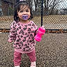 Jaylannie is registered to the contest to win money with this photo: toddler, child, pacifier, pink_sweater, floral_pattern, pink_pants, sippy_cup, playground, outdoor, chain_link_fence, trees, shoes, standing, happy, smiling, young_child, casual_clothing, daytime, person, cute