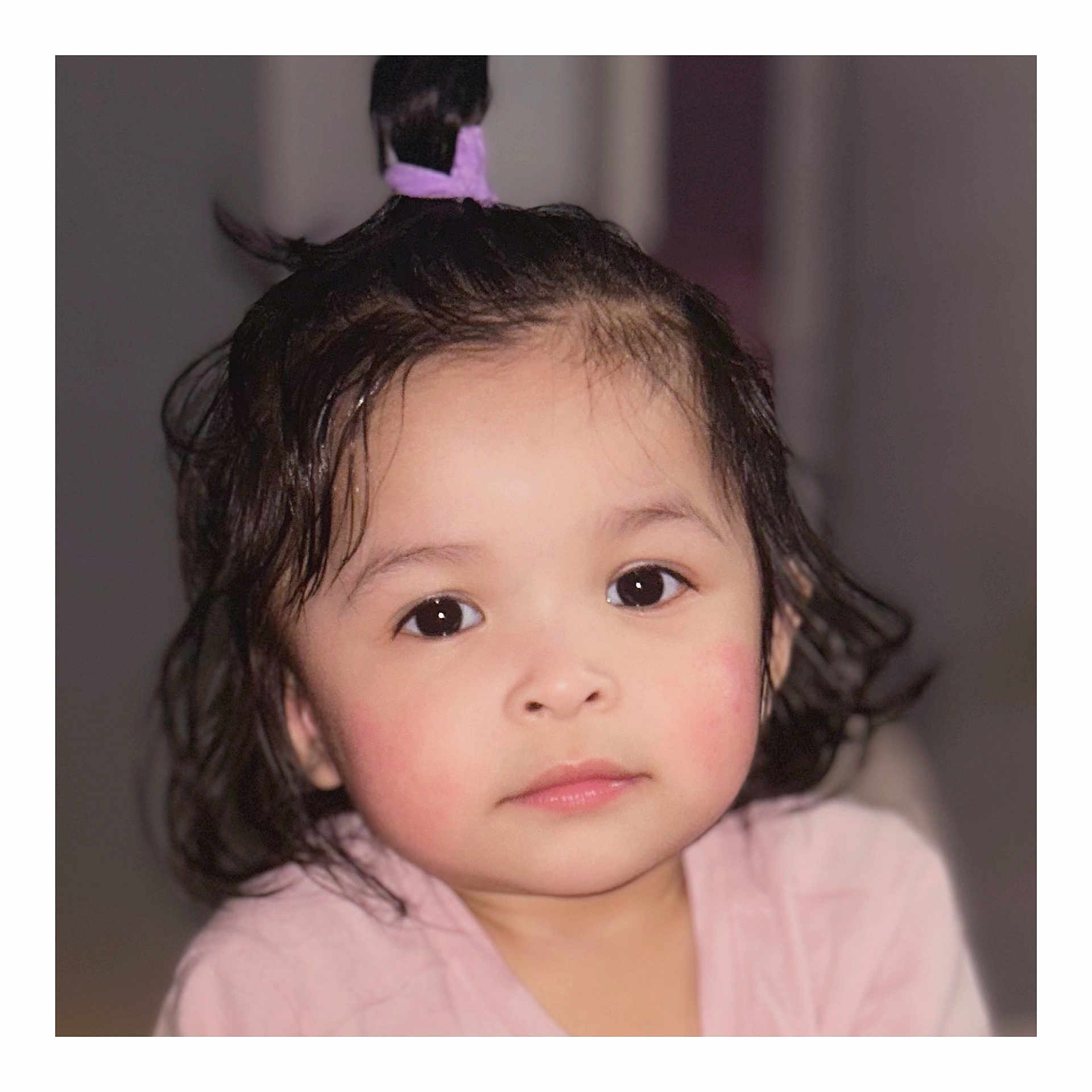 Jaylannie is registered to the contest to win money with this photo: child, toddler, portrait, face, eyes, cheeks, hair, ponytail, pink_clothing, skin, indoors, close_up, cute, soft_lighting, baby_hair, neutral_expression, curly_hair, blush, innocence, headshot