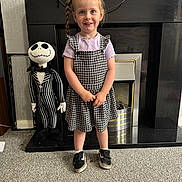 Robyn joined the competition — help win amazing prizes! child, girl, braids, dress, checkered, sneakers, plush_doll, striped, fireplace, carpet, indoor, smiling, person, toy, home, standing, cute, happy, decor, cozy