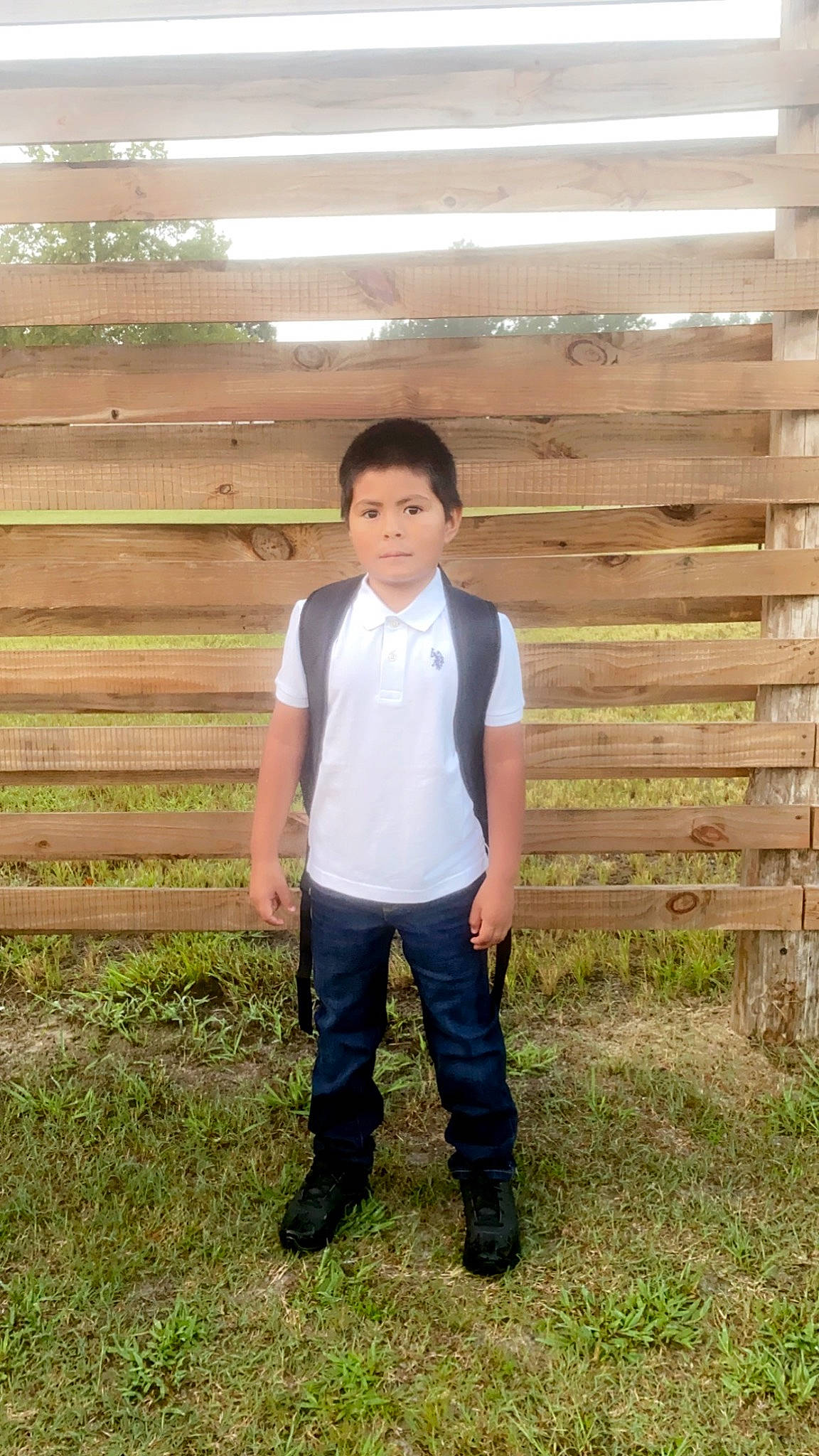 Ulises is registered to the contest to win money with this photo: denim, dress_shirt, face, fence, formal_wear, fun, grass, grassland, happy, home_fencing, landscape, leg, leisure, people_in_nature, person, plant, sleeve, standing, t_shirt, waist